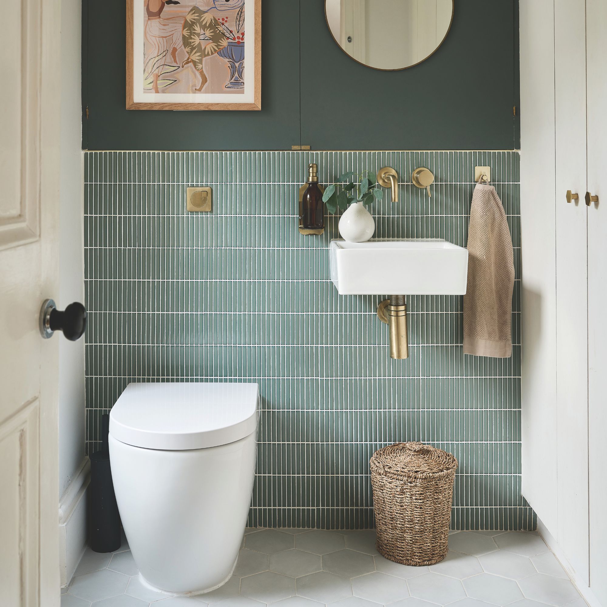 Green bathroom with green tiles above a wall-mounted toilet and sink, with gold fixtures