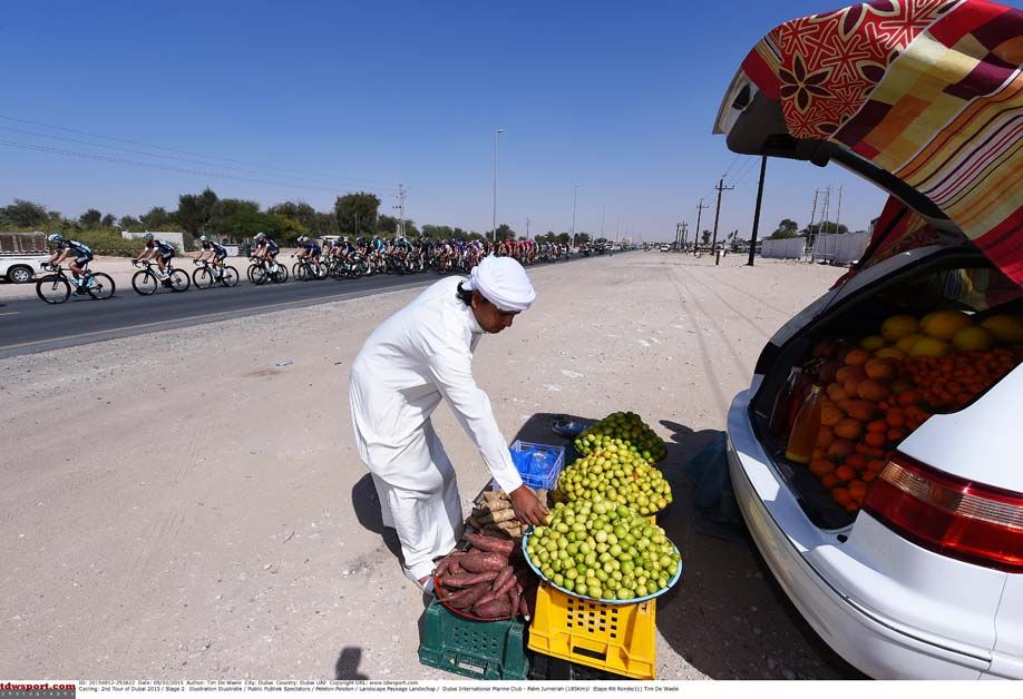 A men sells fruit out of the back of a car during the Tour of Qatar