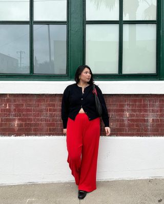 STILVOLLE CARDIGAN-OUTFITS FÜR DEN HERBST 2024: Marina trägt eine rote Hose und eine schwarze Strickjacke