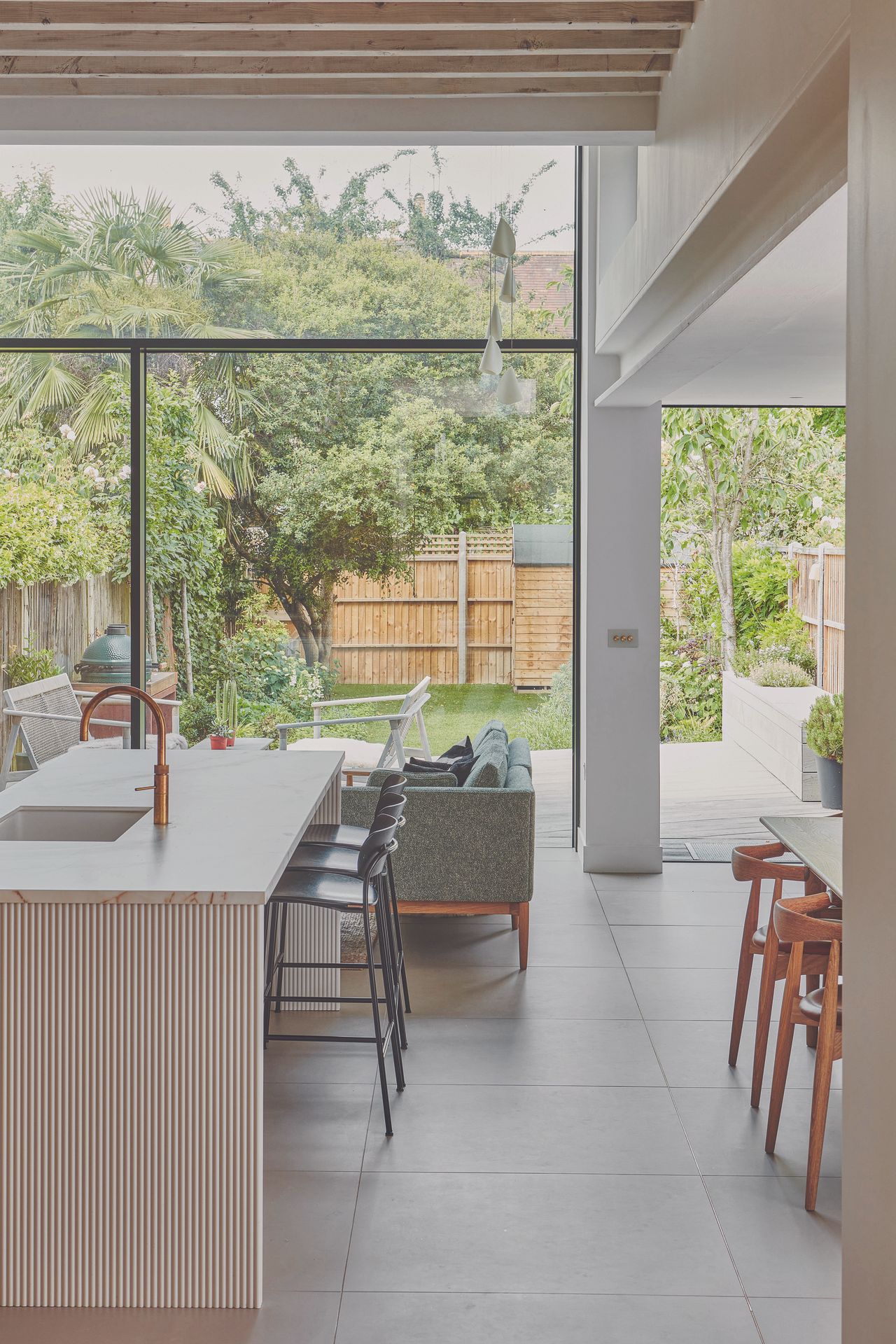 A light and spacious kitchen looking out through a large glass wall to the garden