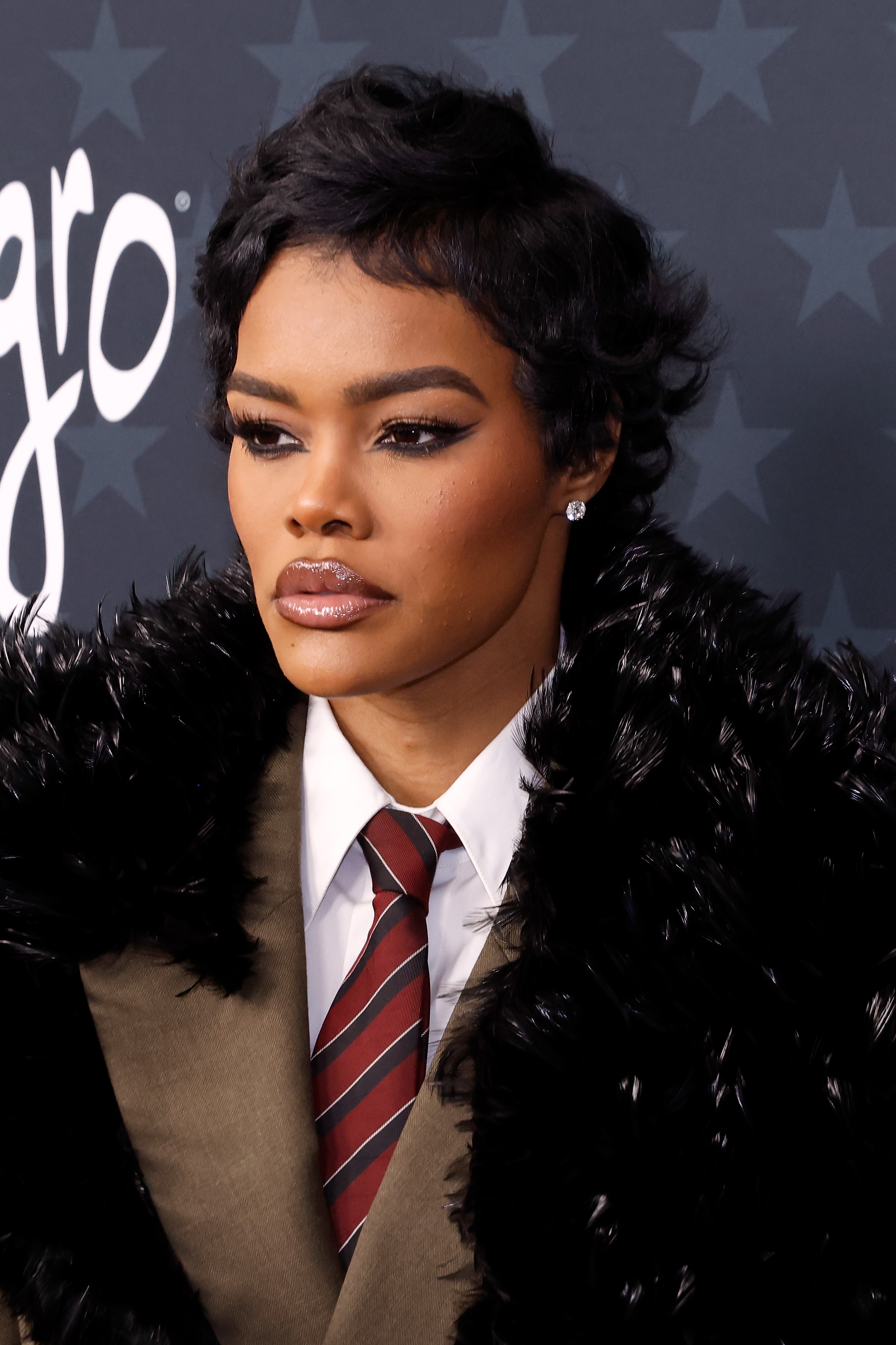 a black woman with short, black hair poses on a red carpet during an awards show