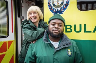 Bloods: Wendy (Jane Horrocks) and Maleek (Samson Kayo) in uniform outside an ambulance. Wendy is leaning on Maleek's shoulder.