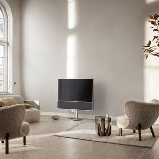 Beovision Contour TV surrounded by neutral chairs in a minimalist bedroom