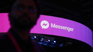 A man walks past a logo of Facebook messenger