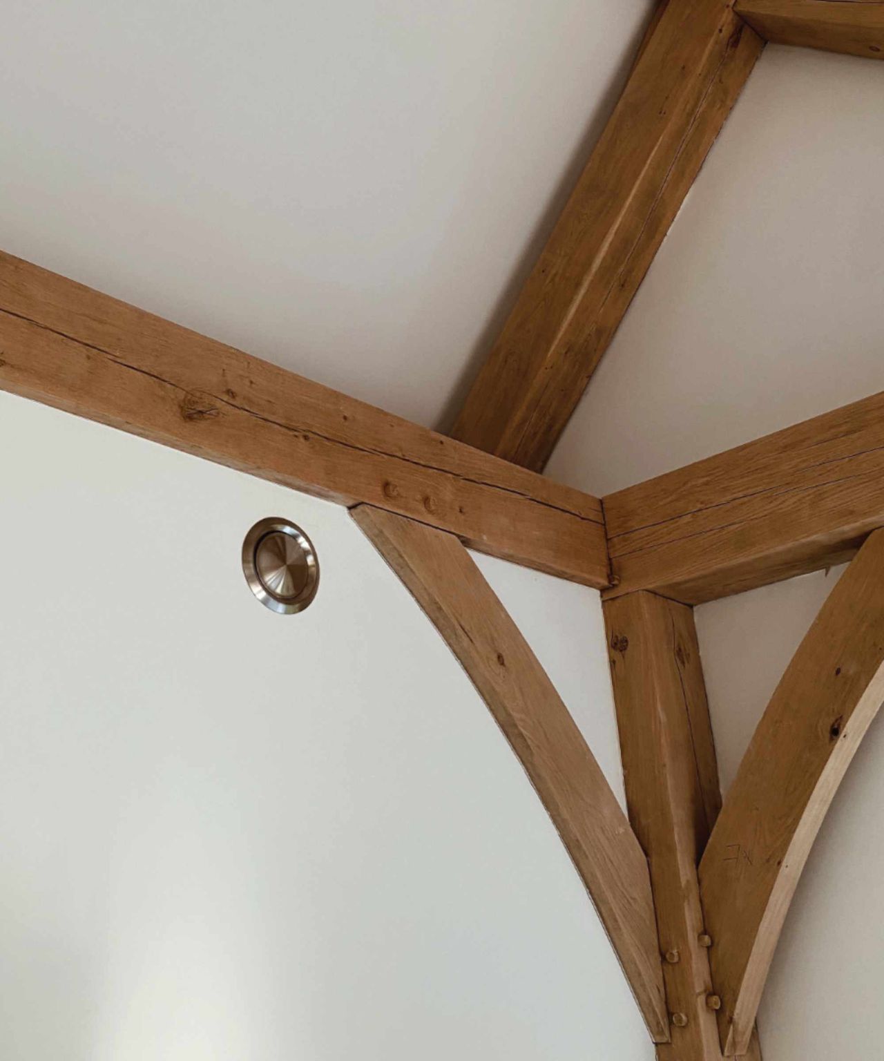 The wall of an oak frame living space with a metal MVHR vent from Rega Ventilation shown