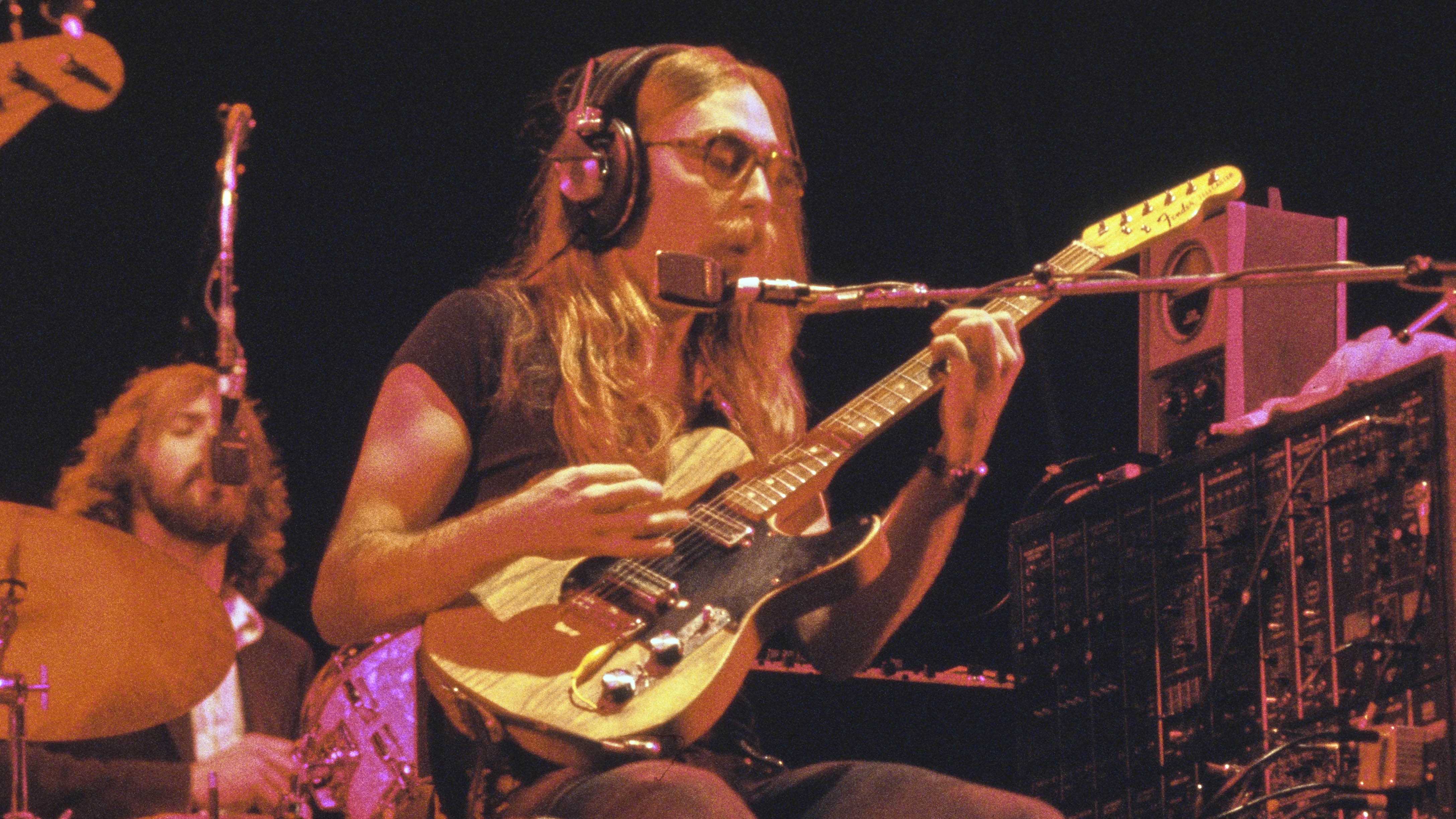 American guitarist Jeff 'Skunk' Baxter, playing a Fender electric guitar, performs live in concert with his band, American rock band The Doobie Brothers, circa 1975. The band's drummer, Keith Knudsen, is seen in the background. (Photo by Richard E. Aaron/Redferns/Getty Images)
