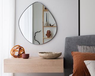 a scandi style room with a wooden nightstand black mirror and bed