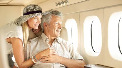 A rich couple looks out the window of a private jet.