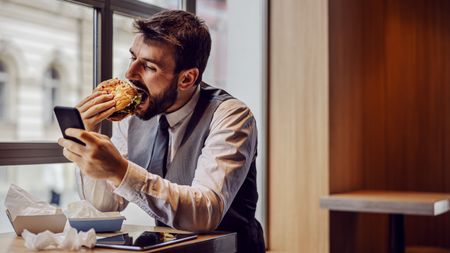 a photo of a man eating staring at his phone