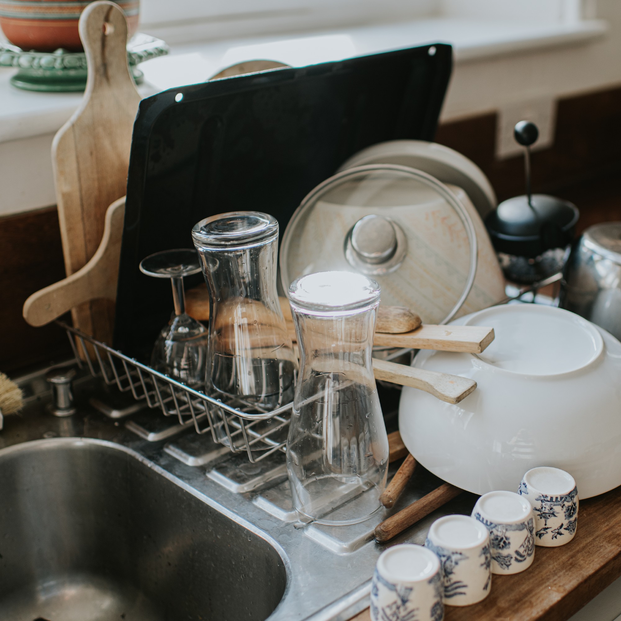 Clean dishes, glasses and utensils stacked on a draining board in a kitchen
