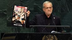 Iranian President Masoud Pezeshkian holds up a picture of a school that was bombed during Israeli and American airstrikes