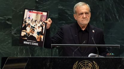 Iranian President Masoud Pezeshkian holds up a picture of a school that was bombed during Israeli and American airstrikes