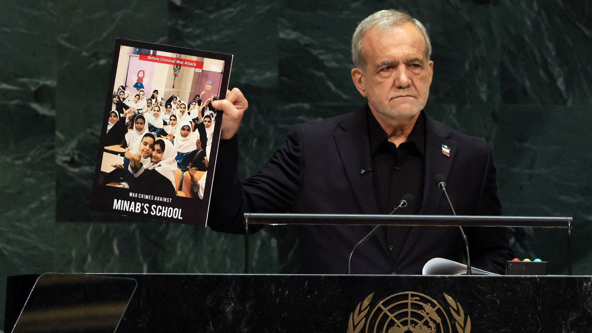 Iranian President Masoud Pezeshkian holds up a picture of a school that was bombed during Israeli and American airstrikes