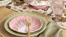 Spring tablescape featuring dinnerware in pastel green and pink hues, accented by woven plate chargers and golden flatware
