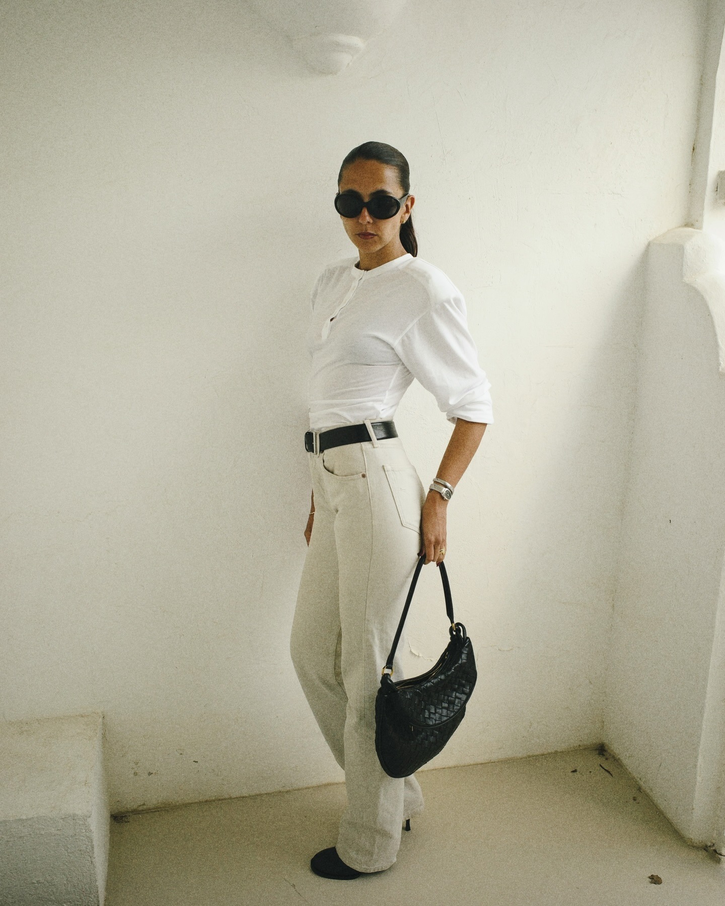 @hannamw wearing a white T-shirt, high-waisted white jeans, and ankle boots.