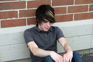 A boy sits outside a school building.