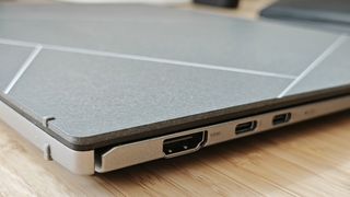 A silver ASUS Zenbook S 13 OLED laptop sitting on a wooden desk