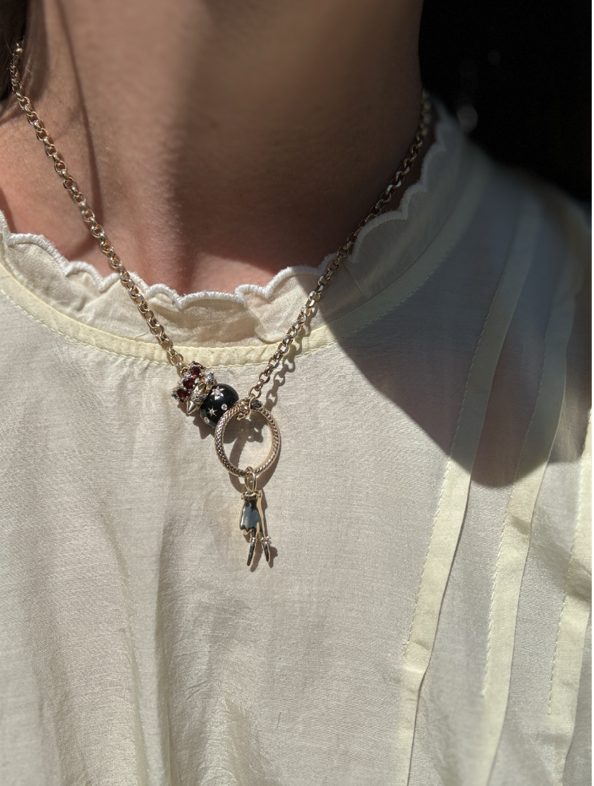 gold necklace with charms on white blouse