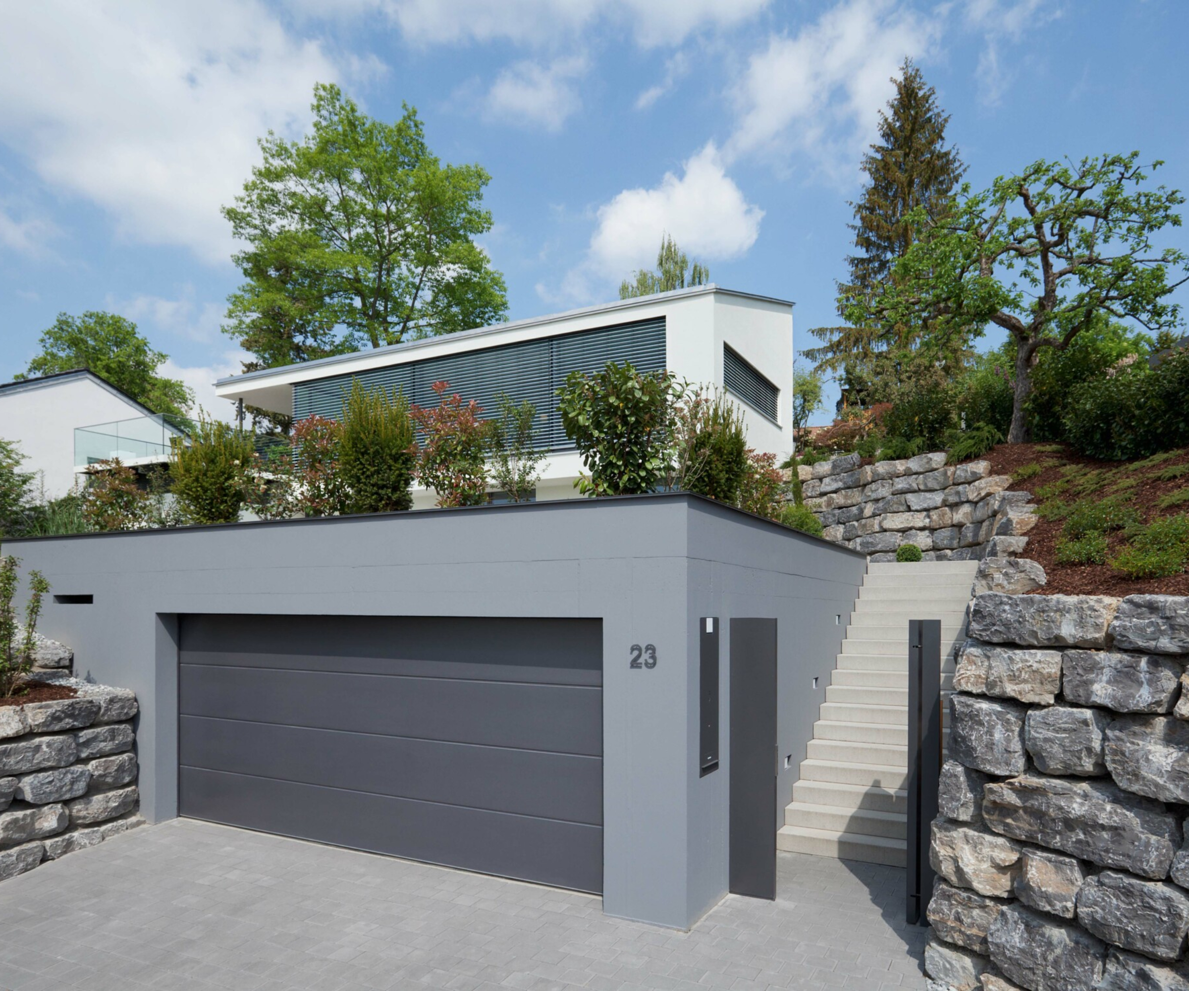 grey paved driveway in front of grey rendered garage with grey door
