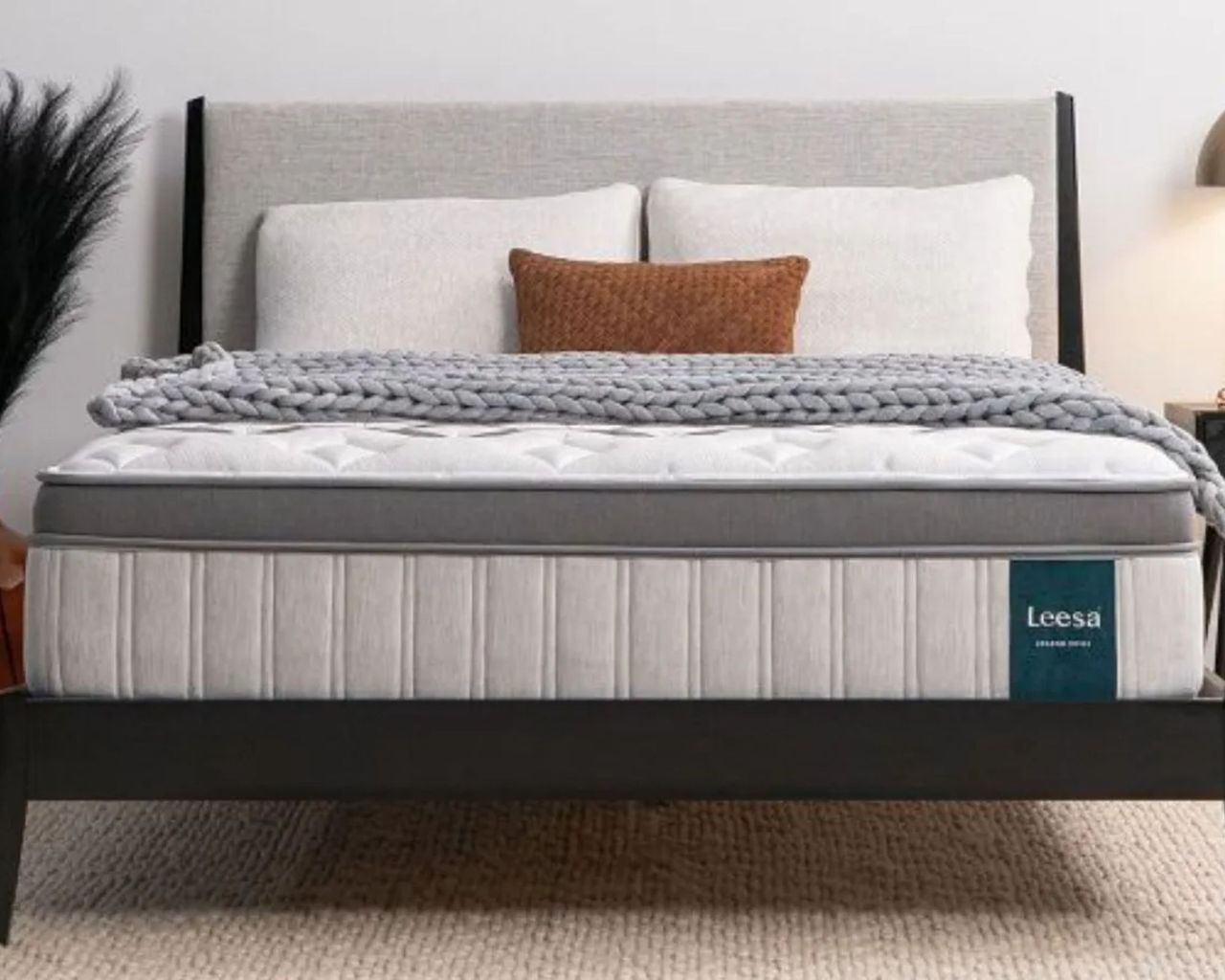 Leesa Legend Chill Hybrid Mattress on a black bedframe with a gray upholstered headboard. Beneath the bed is a pale beige carpet.