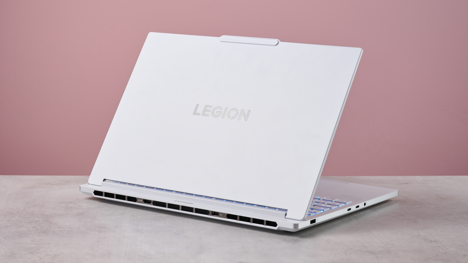 Rear three-quarter view of Lenovo Legion 7i Gen 10 open on desk with pink wall in background