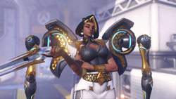 Screenshot of Overwatch hero Domina, a woman in a sleek business suit and black hair, holding a futuristic gun while smirking into the camera.