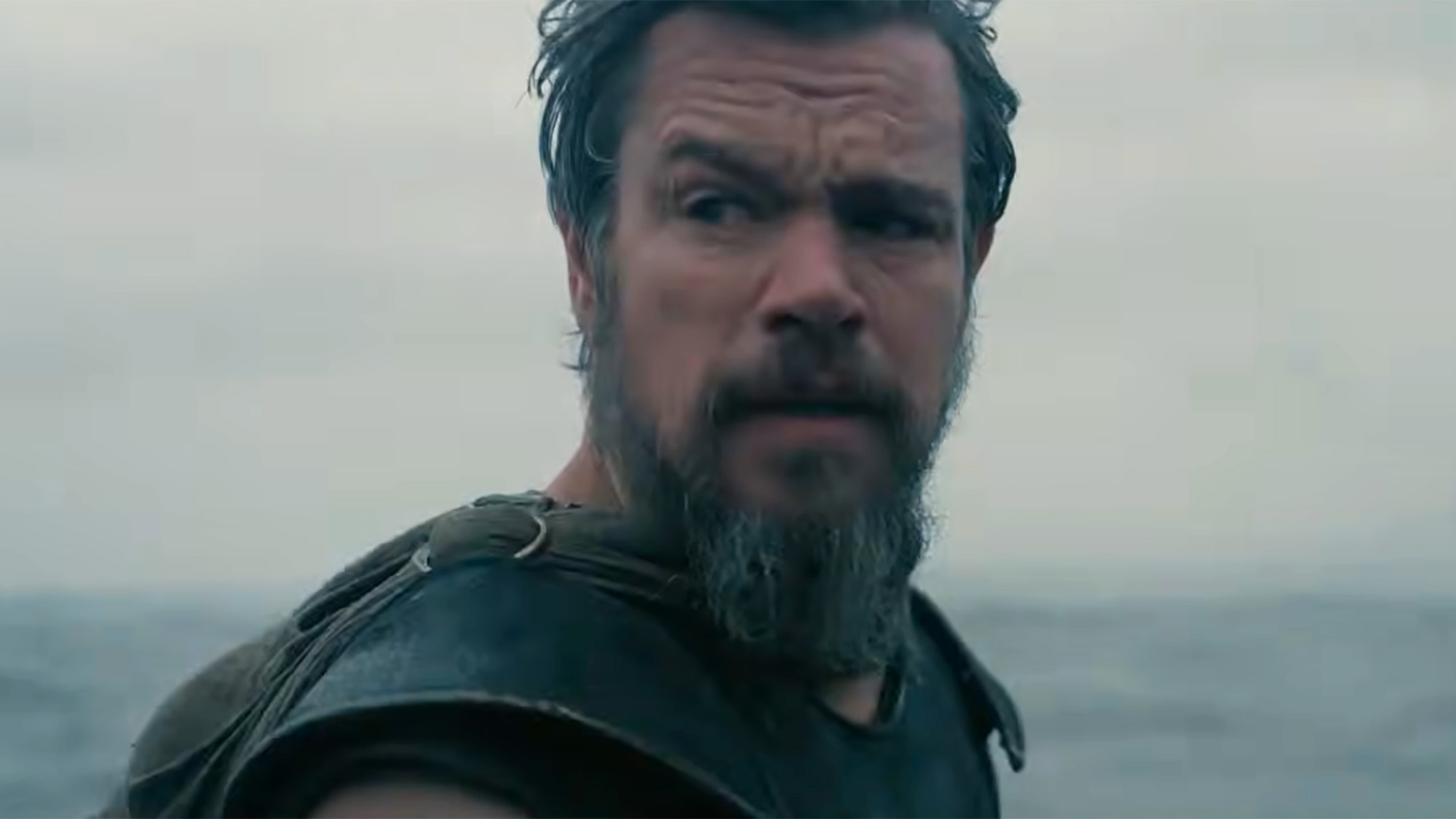 Matt Damon looking back at his men wearing full armour as the ocean looms.