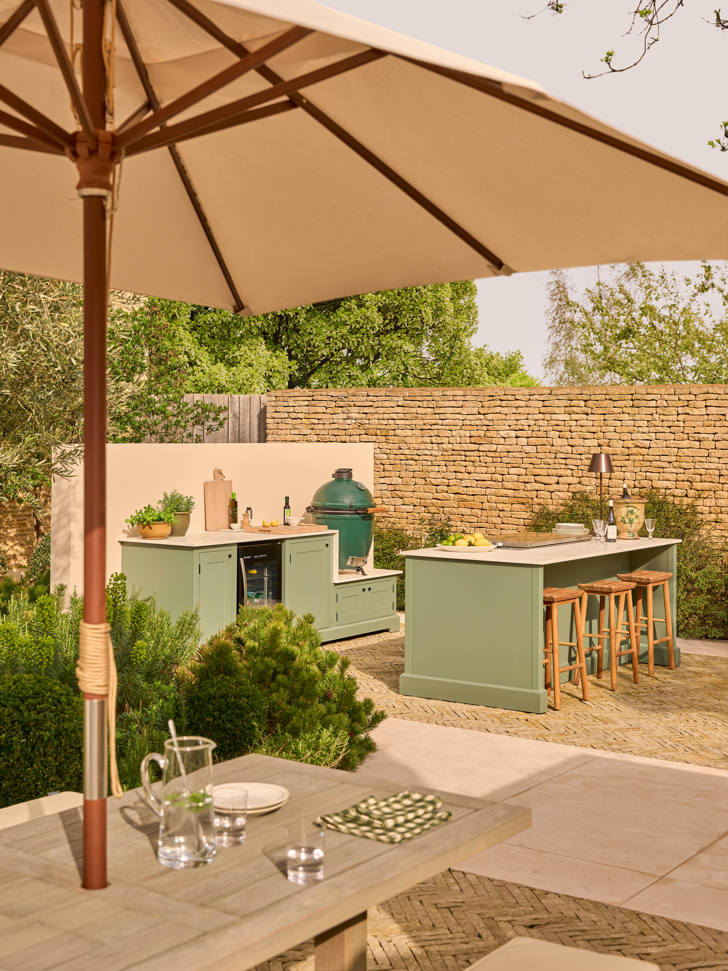 sage green outdoor kitchen with bar seating and a big green egg in the corner