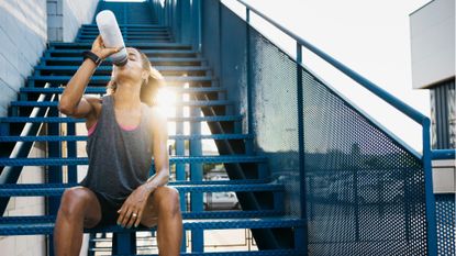 Woman exercising in the heat, drinking from water bottle in the sunshine