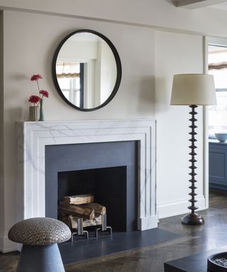 A living room mirror idea with Otto Schulz circle mirror over modern marble fireplace