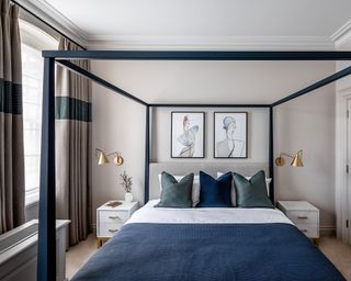 A bedroom with navy four poster bed and warm grey walls