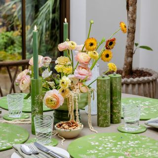 patterned green table placemates on table with flowers, salt and pepper shaker and candle holders