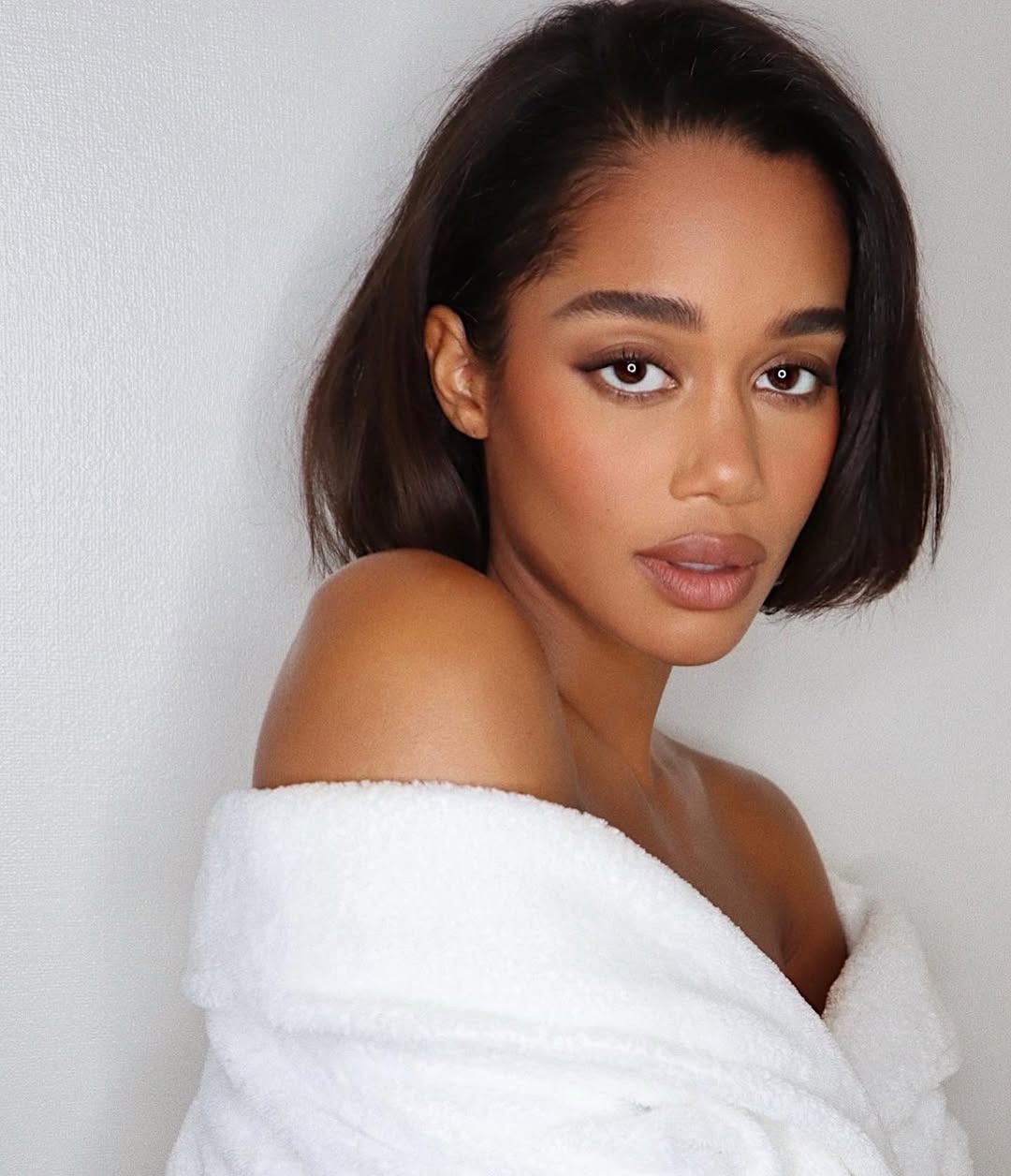 Laura Harrier posing wearing a robe and smoky brown eye makeup.