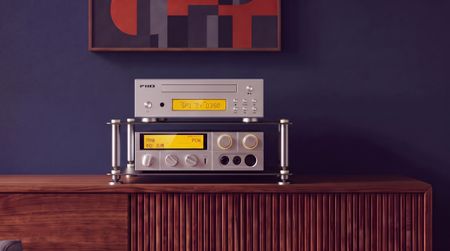 Fiio's CD player in silver on a wooden table, on a hi-fi rack with a blue wall and artwork in the background