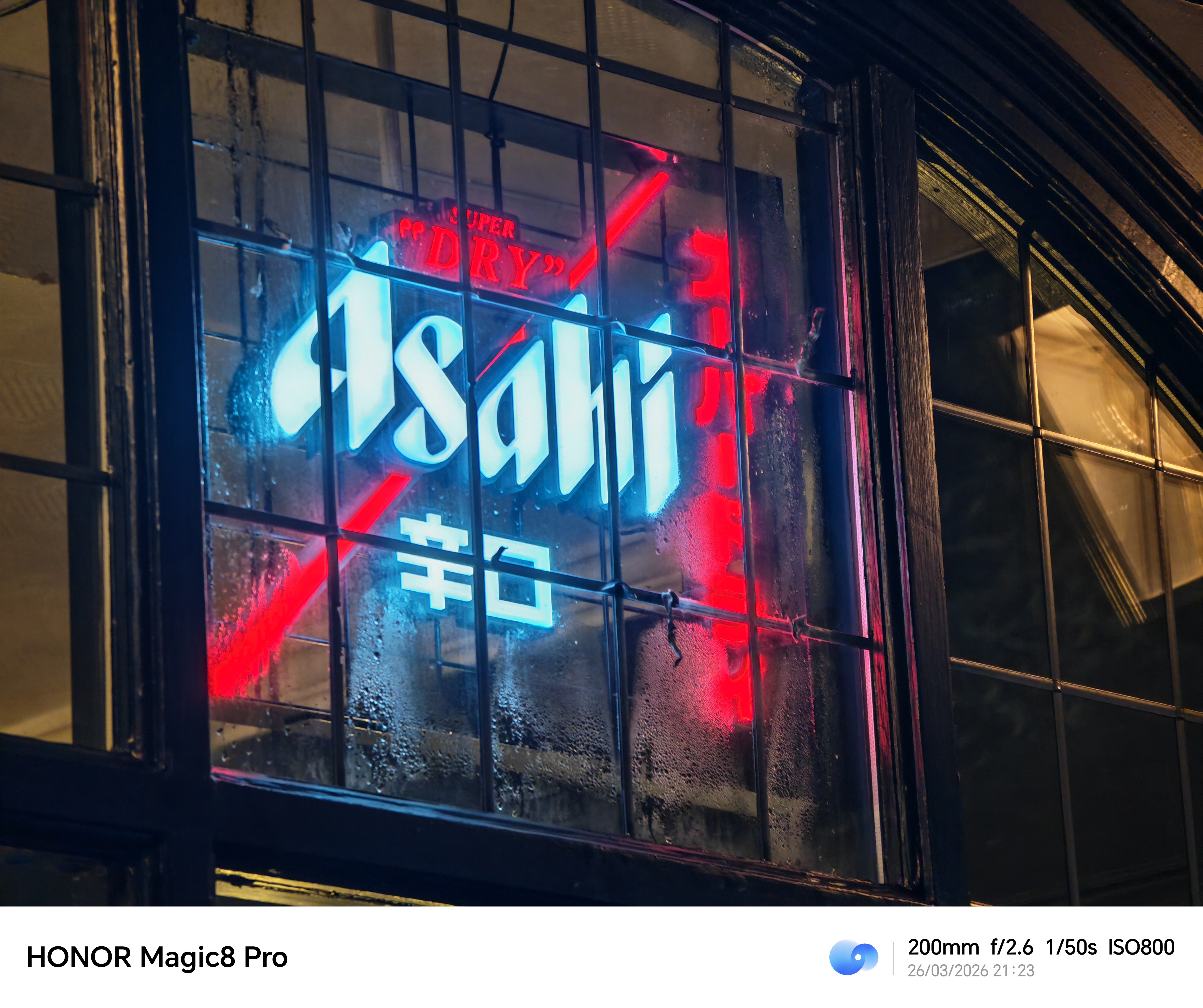 Neon Asahi sign glowing through a rain-speckled window, shot on the Honor Magic8 Pro