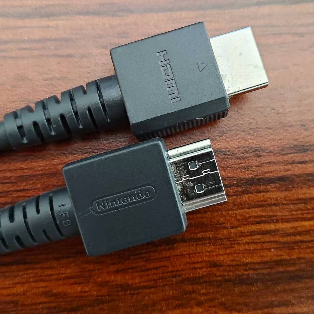 Nintendo HDMI cable on woodgrain desk.