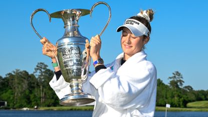 Nell Korda in a bathrobe holds aloft the Chevron Championship trophy in 2024 