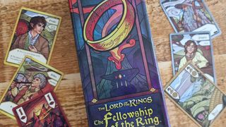 Fellowship of the Ring: Trick-Taking Game box surrounded by cards, all lying on a wooden surface