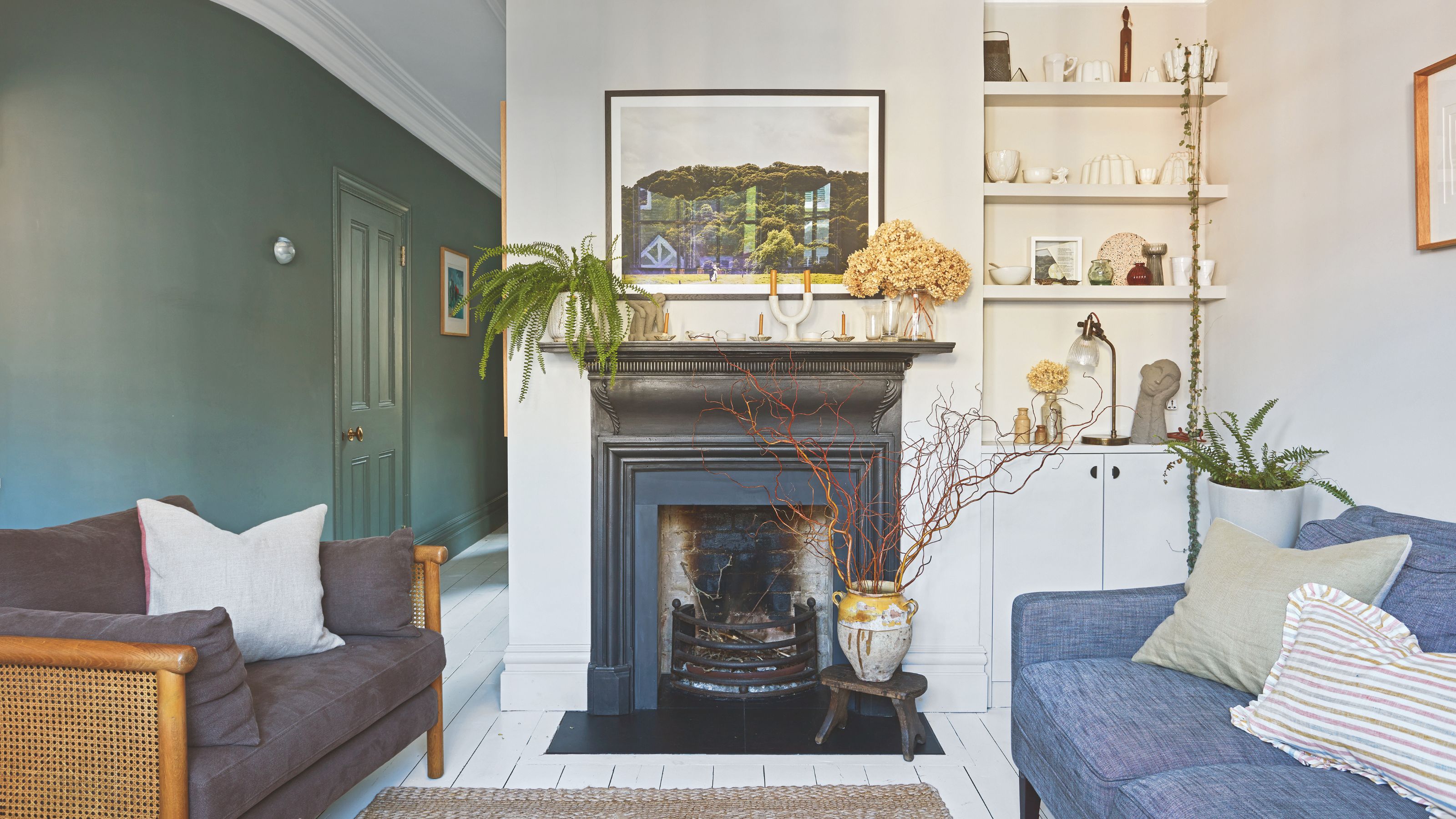 White painted living room with a blue and grey sofas either side of a black fireplace