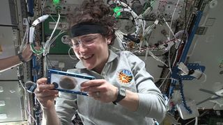 NASA astronaut Christina Koch inspects the first of DoubleTree by Hilton's chocolate chip cookies to be baked using Zero G Kitchen and Nanoracks' Zero G Oven on board the space station.