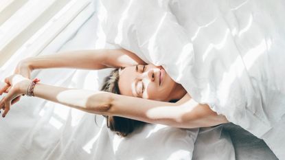 A woman stretching in bed in the morning