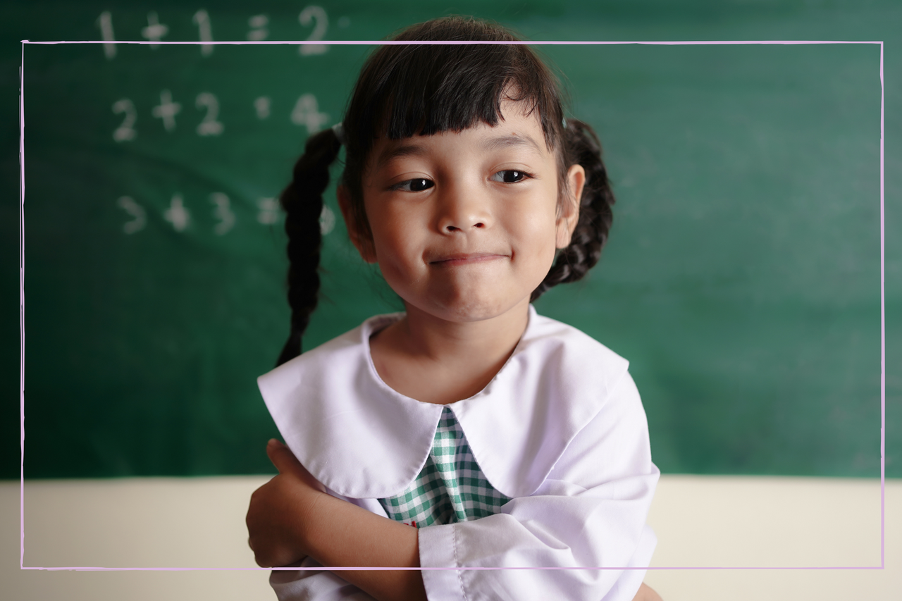 Asian female student standing in front of classroom at school