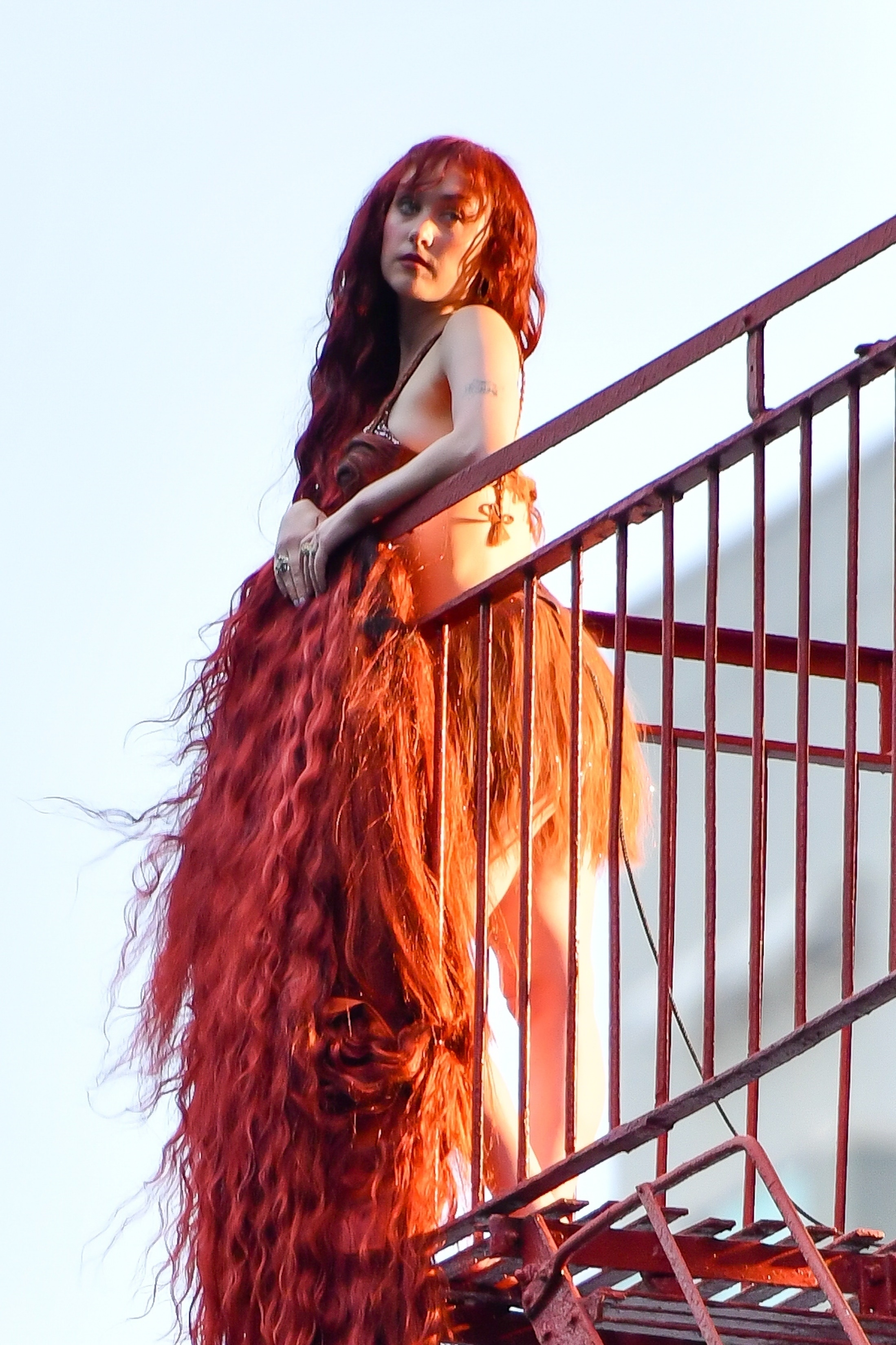 Chappell Roan standing on a fire escape in New York City wearing long, red hair.