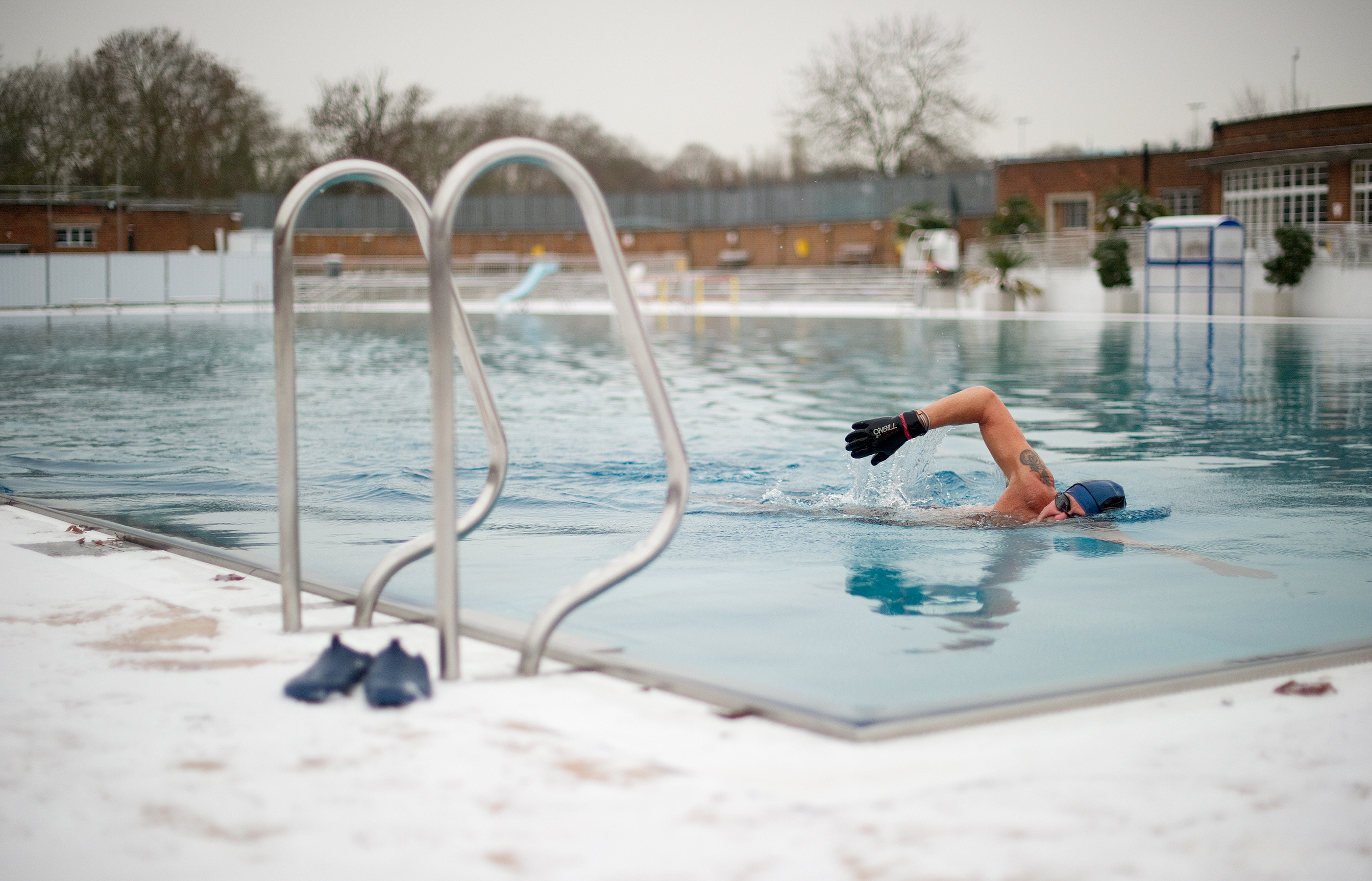 an image of a man swimming in the unheated outdoor lido on Parliament Hill in North London in December