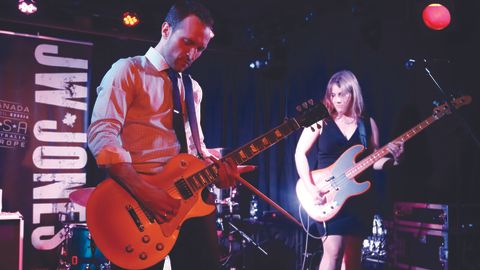 JW Jones playing guitar, next to bass player Laura Greenberg, on stage