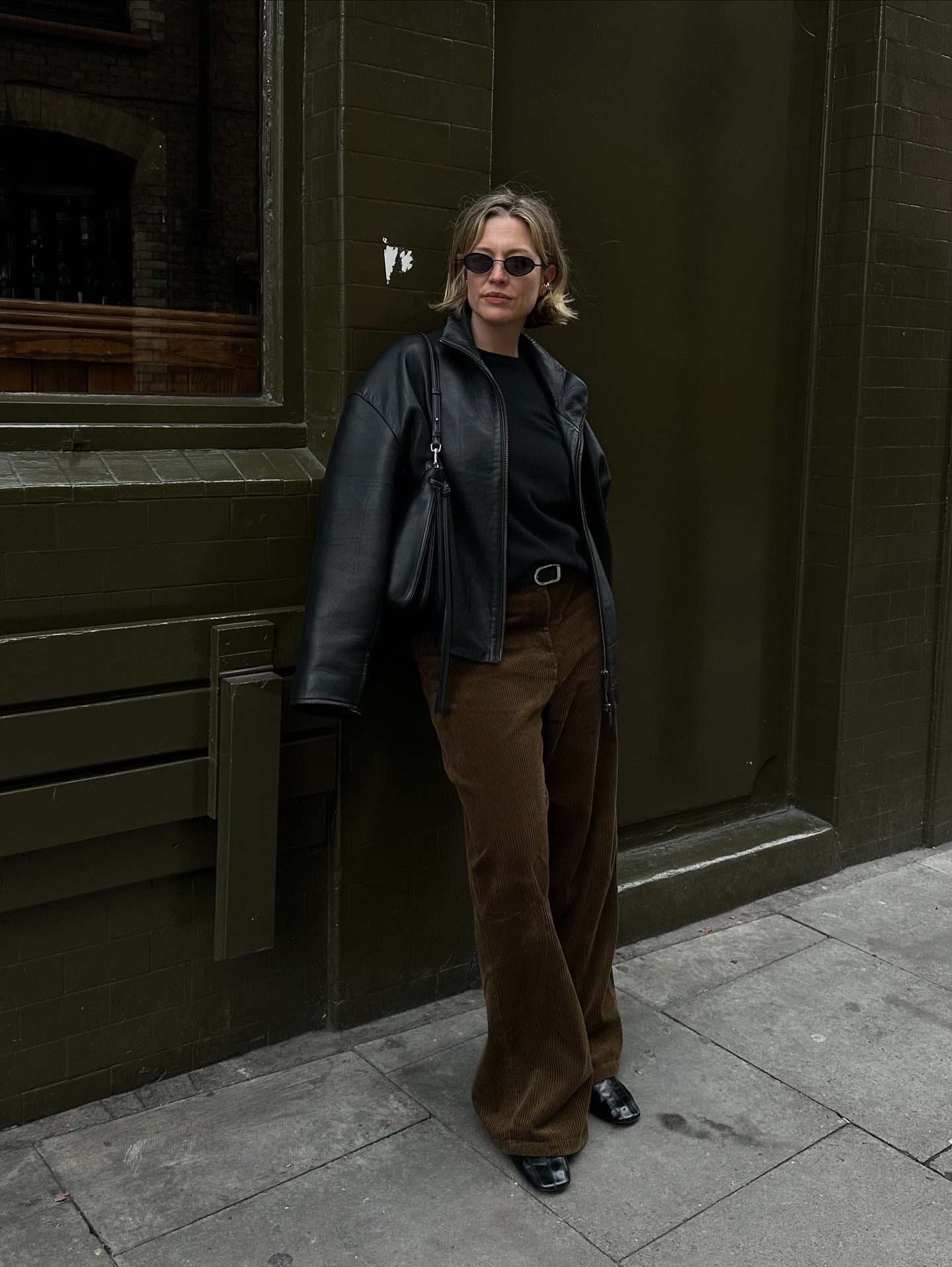 Influencer @alexisforeman wears brown corduroy trousers with a black leather jacket and black leather loafers.