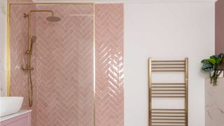 pink herringbone bathroom wall tiles with brass shower and brass towel warmer