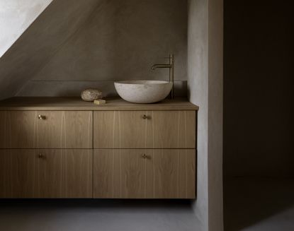 A bathroom with a wooden vanity and stone vessel 
