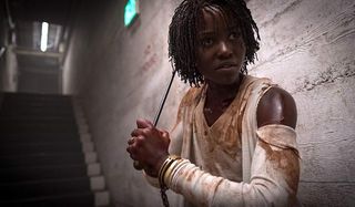 Us Lupita N'yongo holding a weapon as she makes her way underground