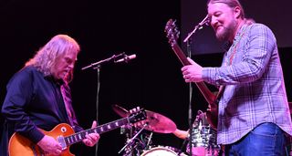 Warren Haynes [left] and Derek Trucks trade licks onstage. Haynes wears a dark shirt and plays a Les Paul in Heritage Cherry while Trucks wears a plaid shirt and plays his trusty Dickey Betts SG.